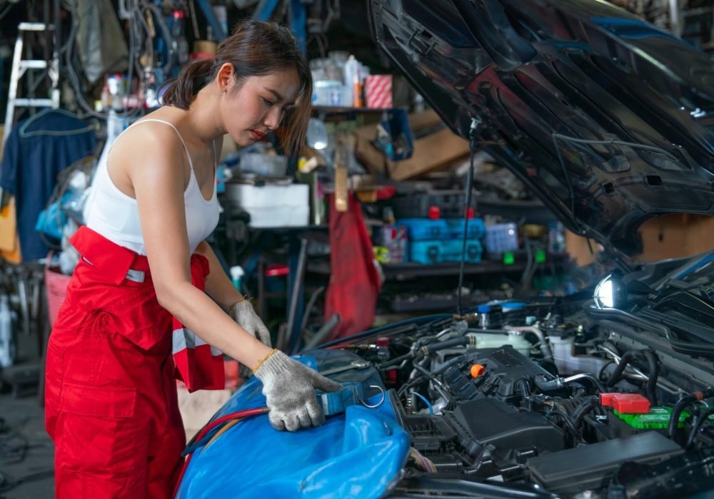 Asian mechanic woman or technician use tools to monitor pressure and gas of car engine and she also look to gauge to analysis and maintenance the car in garage.